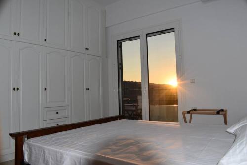 a bedroom with a bed with a sunset in the window at Icaria Great Filling House in Évdhilos
