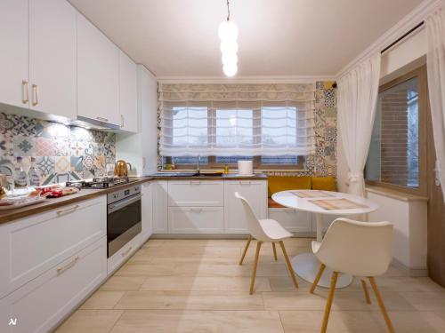 a kitchen with white cabinets and a table and chairs at First Apartments in Focşani