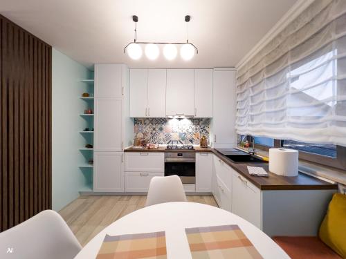 a kitchen with white cabinets and a table and chairs at First Apartments in Focşani
