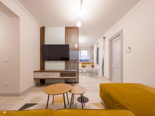 a living room with a bed and a tv and stool at First Apartments in Focşani