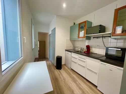 une cuisine avec des placards blancs et une grande fenêtre dans l'établissement Capitole, Grand T1 bis, lumineux, neuf., à Toulouse