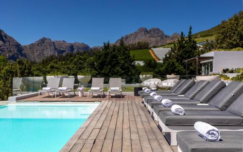 a pool with chaise lounge chairs and a swimming pool at Clouds Estate in Stellenbosch