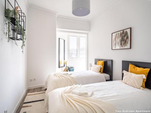 two beds in a room with white walls and yellow pillows at Akicity Campolide Sun in Lisbon