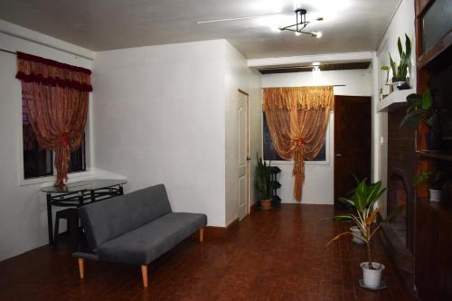 uma sala de estar com um sofá e duas janelas em By the Old Swing em Baguio