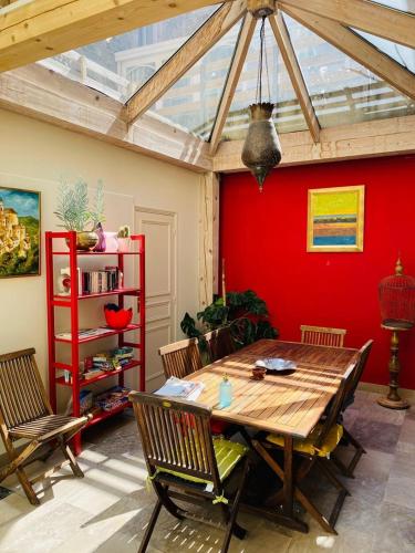 une salle à manger avec une table en bois et un mur rouge dans l'établissement La Notre Dame Conciergerie Leroy, à Boulogne-sur-Mer