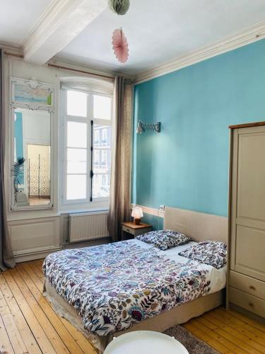 une chambre avec un lit et un mur bleu dans l'établissement La Notre Dame Conciergerie Leroy, à Boulogne-sur-Mer