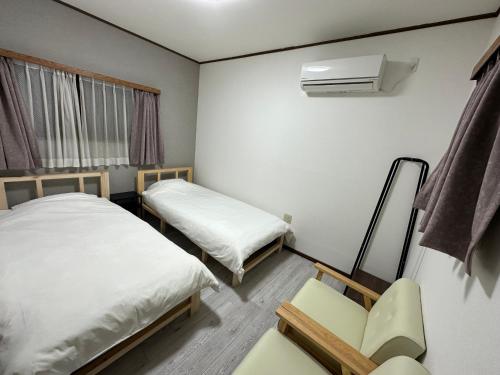 a small room with two beds and a chair at ゴーゴーマリンホテル 東京千葉館山 in Tateyama