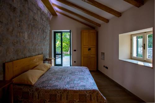 - une chambre avec un lit et un mur en briques dans l'établissement La Dorada Holiday Home, à Trsteno