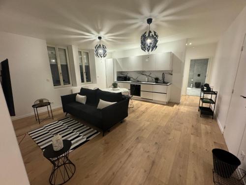 un salon avec un canapé noir et une cuisine dans l'établissement Appartement VIII - Haut Standing proche Luxembourg et Cattenom, à Nilvange