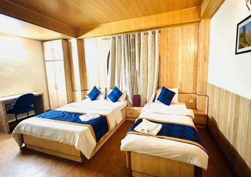 a bedroom with two beds and a window at Dhe Kyi Khang by Magwave Hotels-100 Mts from MG Marg in Gangtok