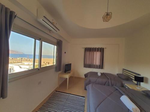 Al Deira Dahab Residence في دهب: غرفة نوم بسريرين ونافذة كبيرة
