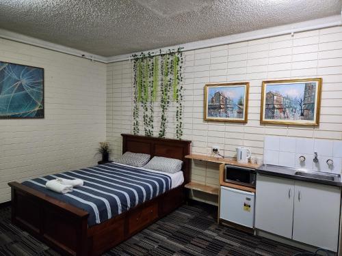1 dormitorio con 1 cama y lavamanos. en West End Motel en Adelaida