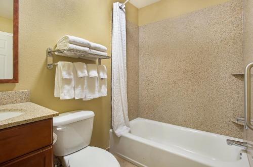 a bathroom with a toilet and a tub and a sink at Candlewood Suites Tuscaloosa, an IHG Hotel in Tuscaloosa