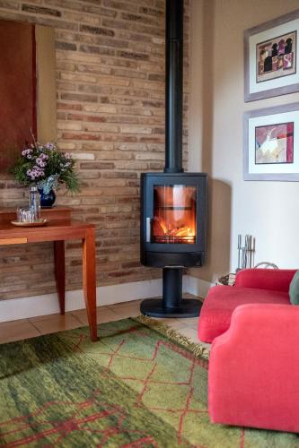 a living room with a fireplace and a red couch at La Torre del Visco - Relais & Châteaux in Fuentespalda