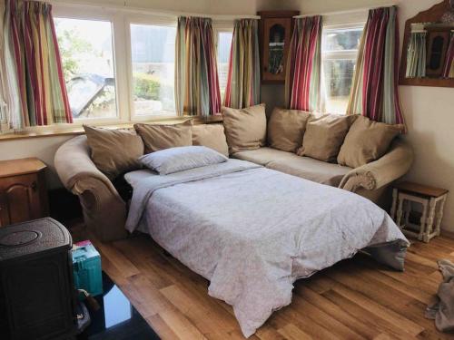 a bedroom with a bed and a couch and windows at Midden Manor: Farm stay in rural County Antrim. in Cullybackey