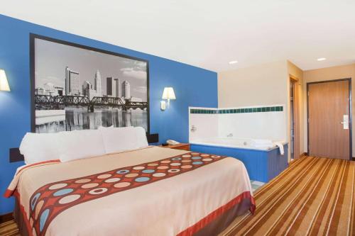 a hotel room with a large bed and a bath tub at Super 8 by Wyndham Defiance in Defiance