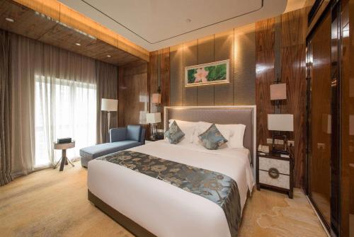 a bedroom with a large white bed and a chair at Ramada Plaza Liuzhou Liudong in Liuzhou