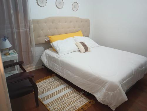 a bedroom with a white bed with a yellow pillow at Cozy- Chic room in a very quiet area in Detroit