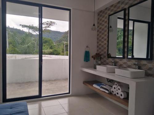 uma casa de banho com 2 lavatórios e uma grande janela em Habitación en casa Rural Campestre em La Vega