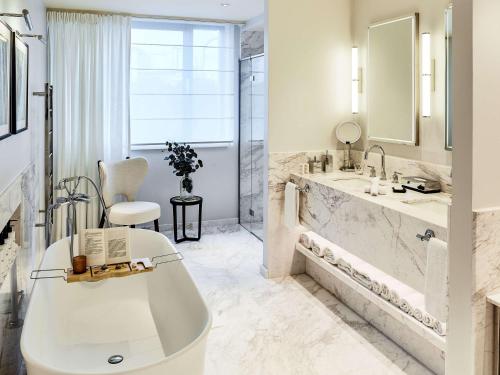 a white bathroom with a tub and a sink at Sofitel Brussels Europe in Brussels