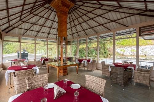 un restaurante con mesas y sillas rojas y ventanas en Tehri Club Resort By DLS Hotels, en Chamba