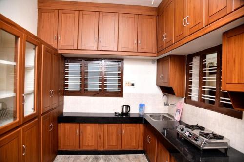 a kitchen with wooden cabinets and a black counter top at Spacious Guesthouse in Nagercoil in Nāgercoil