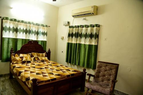 a bedroom with a bed and a window and a chair at Spacious Guesthouse in Nagercoil in Nāgercoil