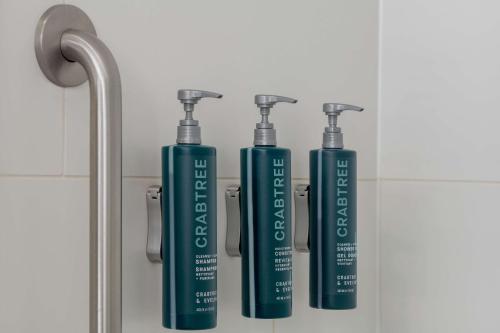 a group of three green shampoo bottles in a bathroom at Hilton Shreveport in Shreveport