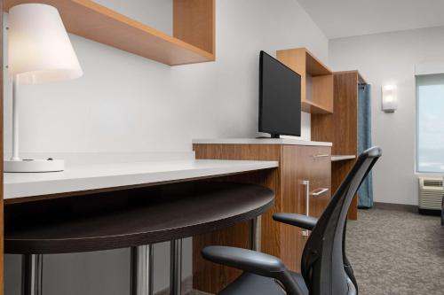 a room with a desk with a chair and a television at Home2 Suites by Hilton Tallahassee State Capitol in Tallahassee