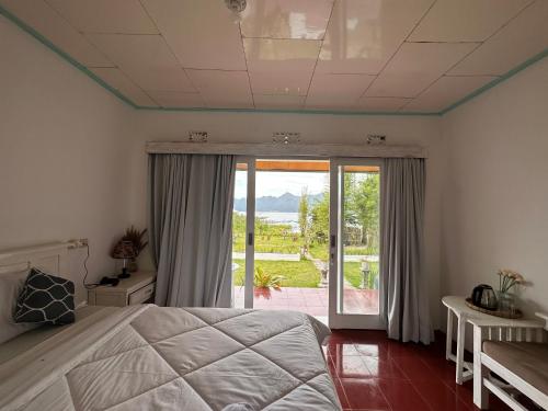 - une chambre avec un lit et une porte coulissante en verre dans l'établissement Gill Lake Batur, à Kubupenlokan