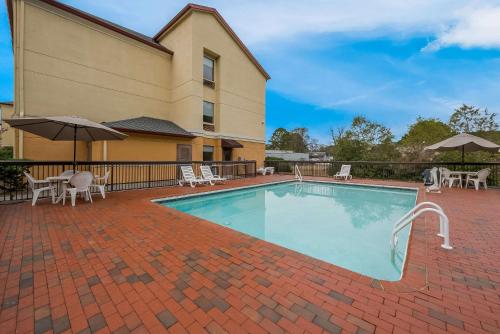 a swimming pool with chairs and umbrellas next to a building at Comfort Inn Fayetteville I-95 in Fayetteville