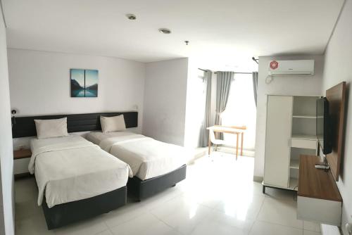 een hotelkamer met 2 bedden en een televisie bij izicozi Hotel Jababeka in Cibeber