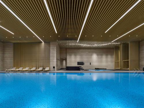 - une grande piscine avec des chaises dans un bâtiment dans l'établissement Hilton Nanjing Niushoushan, à Nankin