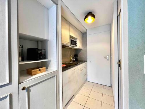 una pequeña cocina con armarios blancos y una puerta blanca en HID AG: Lakeview Studio mit Parkplatz und Balkon, en Därligen