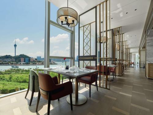 ein Esszimmer mit einem Tisch und Stühlen sowie einem großen Fenster in der Unterkunft Hilton Zhuhai in Zhuhai