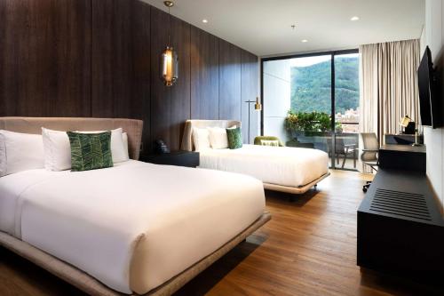 Cette chambre comprend deux lits et une télévision. dans l'établissement Salvio Parque 93 Bogota, Curio Collection by Hilton, à Bogotá