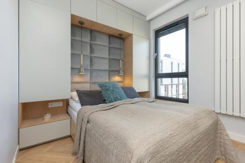 ein Schlafzimmer mit einem großen Bett und einem Fenster in der Unterkunft Bright Blue Apartment with Balcony, Parking and Air Conditioning in Warsaw by Renters in Warschau