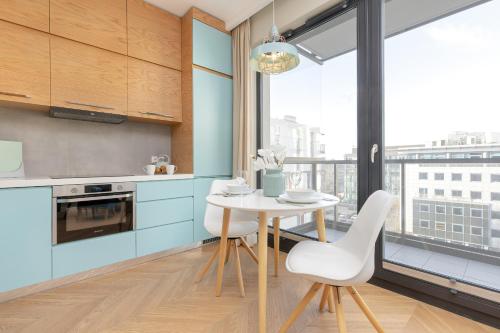 eine Küche mit einem Tisch und Stühlen sowie einem Fenster in der Unterkunft Bright Blue Apartment with Balcony, Parking and Air Conditioning in Warsaw by Renters in Warschau