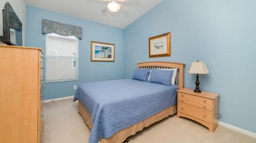 Dormitorio azul con cama y mesita de noche en 4 BR Private Vacation Home, en Kissimmee