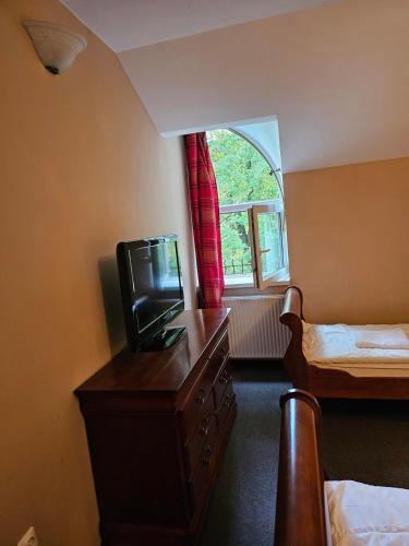 a room with a tv on a dresser and a bed at Kasztanowy Dwór in Cieszyn