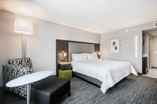 a hotel room with a bed and a table and a chair at Holiday Inn Express & Suites Toronto Airport South by IHG in Toronto