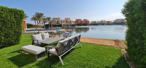 a couple of chairs and a table next to a lake at Luxury 3BR Townhouse, Tawila, El Gouna, Lagoon & Pool access in Hurghada