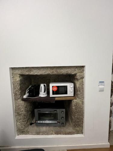 a room with a wall with a fireplace with a microwave at Refúgio Rural Ponte de Lima - Vista Verde e Tranquilidade in Ponte de Lima