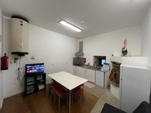 a white kitchen with a table and a refrigerator at Casa em Aldeia rural - Circuito Aldeias de Portugal in Ponte de Lima