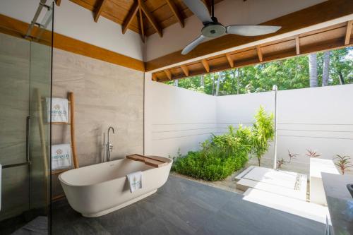 a bathroom with a tub and a glass shower at Emerald Faarufushi Resort & Spa - Deluxe All Inclusive in Raa Atoll