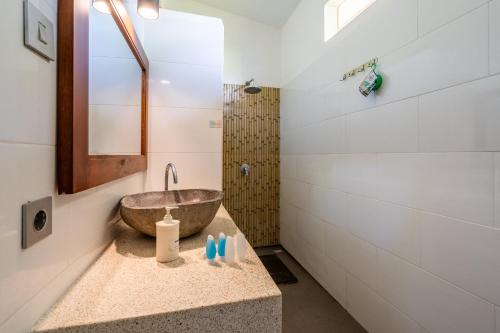 y baño con lavabo de piedra y espejo. en Villa Doria, en Gili Air