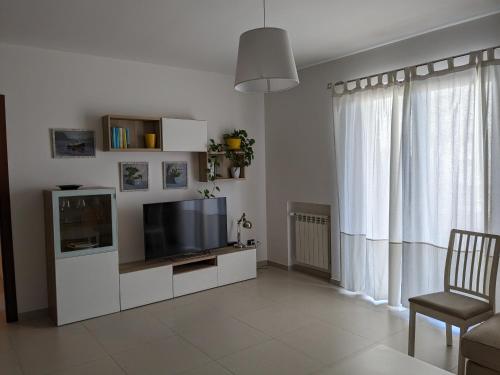 una sala de estar con TV en un centro de entretenimiento blanco en La Casa dei Due Mari - large apartment with parking, en Taranto