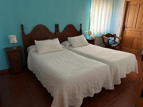 1 dormitorio con 2 camas y pared azul en La casa barata, casa rural, en Cedillo