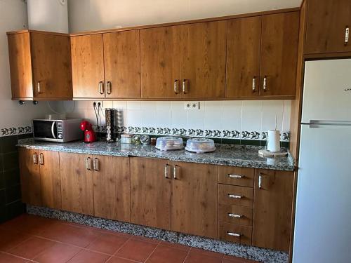 una cucina con armadi in legno e frigorifero bianco di La casa barata, casa rural a Cedillo