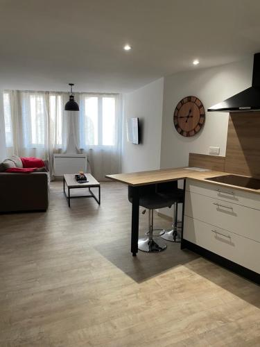 uma cozinha e sala de estar com uma mesa e um relógio em F2 Centre Historique Saint Colomban em Luxeuil-les-Bains